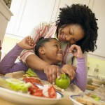 Mother Stands With Her Young Daughter in the Kitchen, Chopping an Apple for Her Lunch