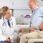 Male Doctor Examining Male senior Patient With Hip Pain