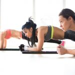 Three attractive sport girls doing plank exercise lying on yoga mat in fitness class.